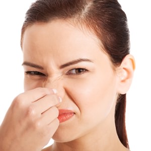 Portrait of a young woman holding her nose because of a bad smell. Isolated on white.